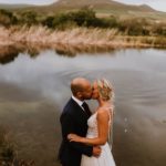 Bride and groom kissing next to dam