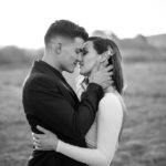 Bride and groom kissing in field